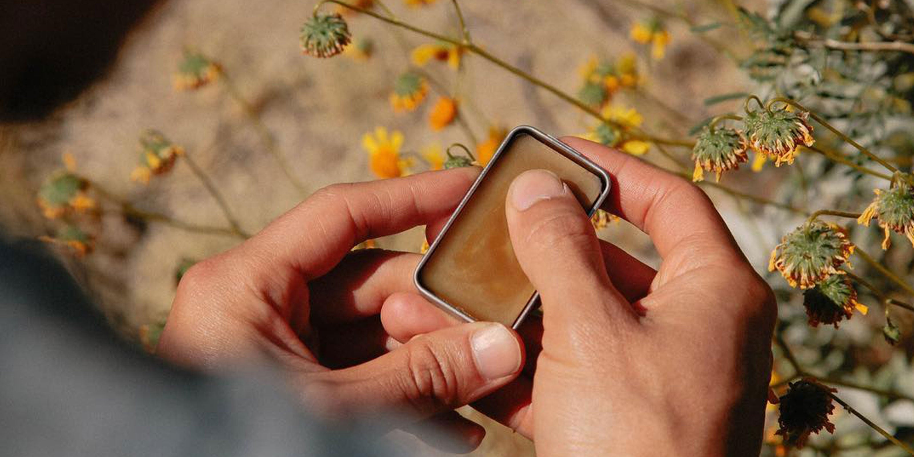 Parfumflakon mit zwei Händen im Hintergrund