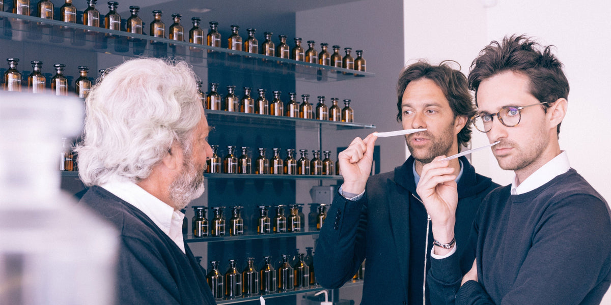 Drei Männer, die an Parfumstreifen riechen